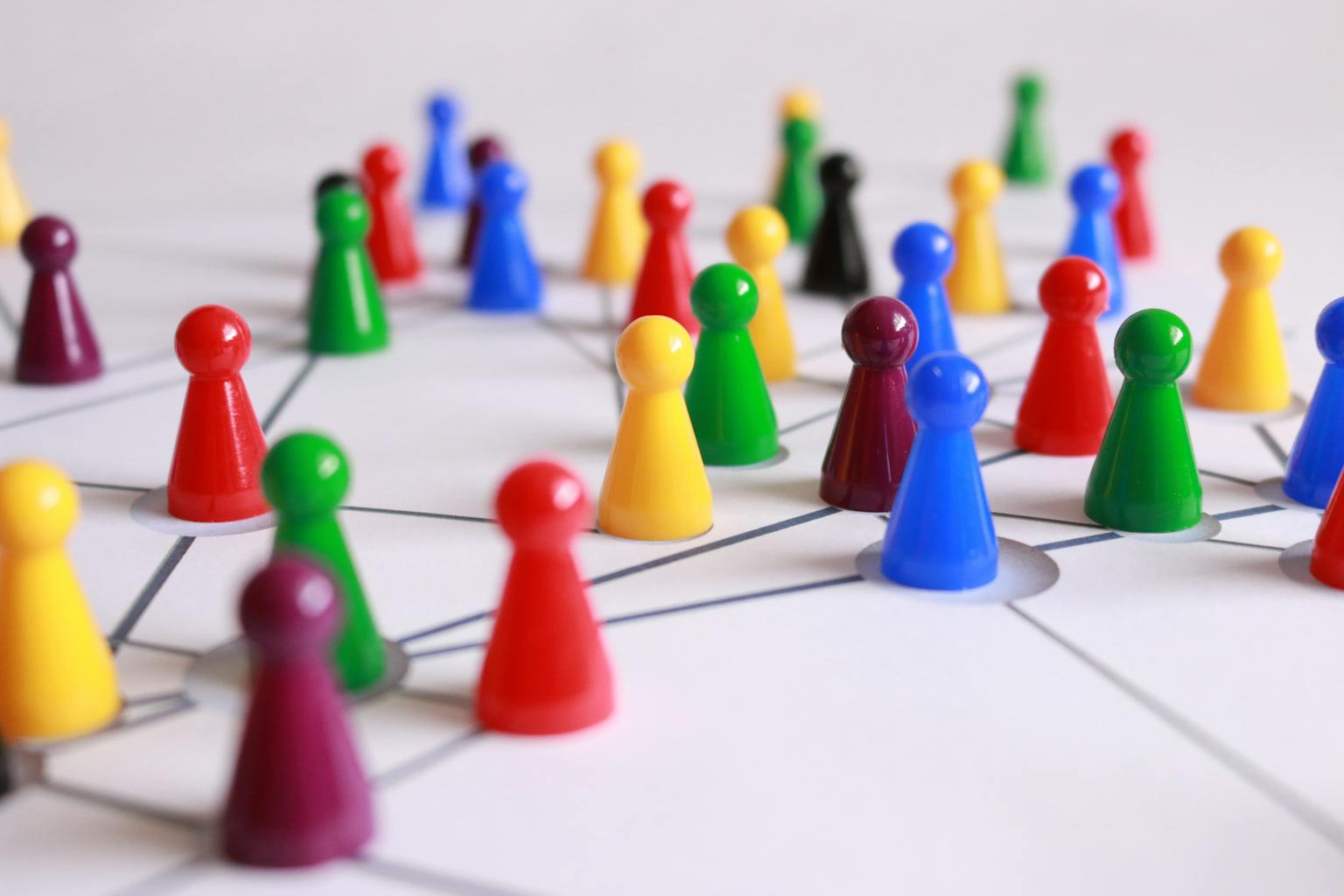 Red de Investigación Koinonia A strategic arrangement of colorful pawns connected on a game board, symbolizing networking and teamwork.