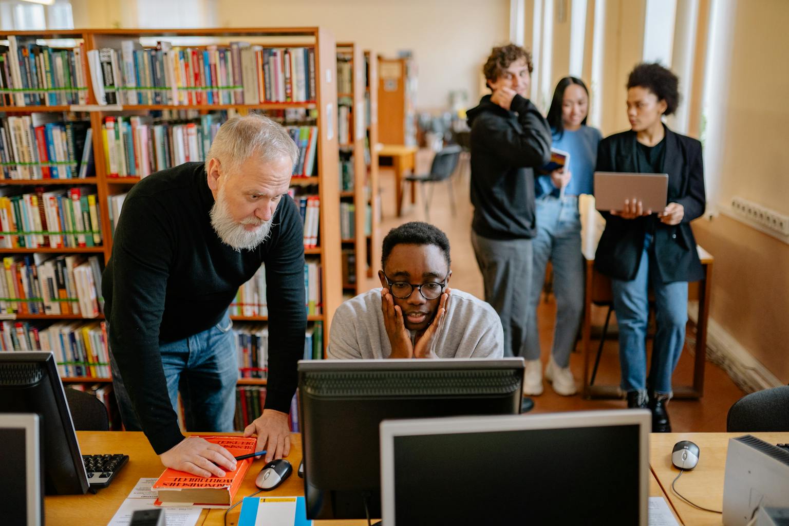Red de Investigación Koinonia Students and a mentor collaborate in a university library, engaging in educational activities.